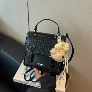 Chic black woven texture backpack for women featuring a cute plush bear charm accessory