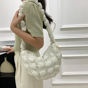 Close-up of white bubble textured crescent bag with ruched strap carried by model