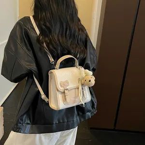 Back view of model wearing a chic cream woven college style backpack with a charm