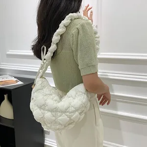 Side view of soft white quilted cloud bag worn by model showing textured ruched strap details