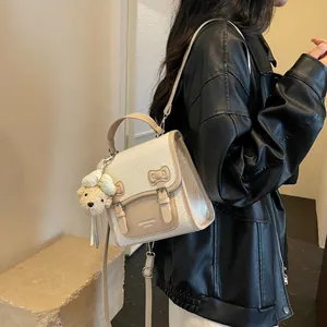 Stylish white and beige preppy style backpack with teddy bear charm shown on model.