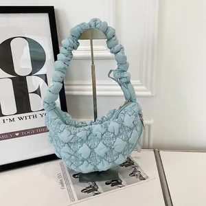 Detail view of a light blue ruched bubble dumpling bag on a stylish display stand