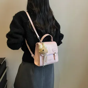 Stylish pink college style backpack with bear charm shown on model in black sweater