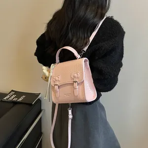 Elegant pink preppy style backpack with woven flap and bow details shown on model back view