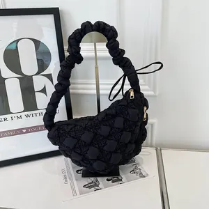 Detail view of a black quilted bubble hobo bag with a ruffled handle on a display stand