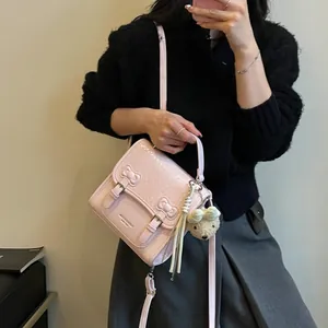 Stylish pink woven crossbody bag for women featuring bow details and a cute bear charm