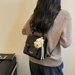 Detailed view of black woven texture college style backpack worn on shoulder with bear charm