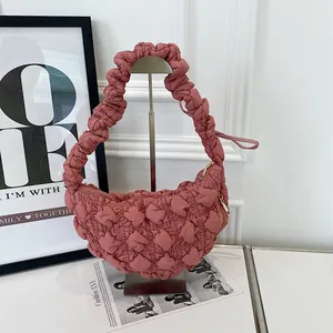 Close-up of dusty rose bubble textured cloud bag on a display stand.