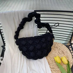 Detail of black quilted puffy cloud bag with scrunchie strap on aesthetic background