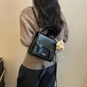Back view of a woman wearing a black woven texture backpack with a cute bear charm