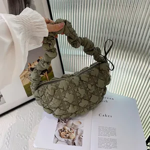 Detailed view of green pleated bubble fabric handbag shown against magazine and decor
