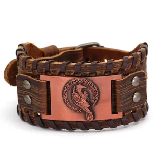 Dettaglio del totem del corvo vichingo su un bracciale in pelle marrone da uomo.