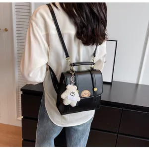 Mannequin élégant portant un sac à dos vintage en cuir noir avec un joli charme d'ours