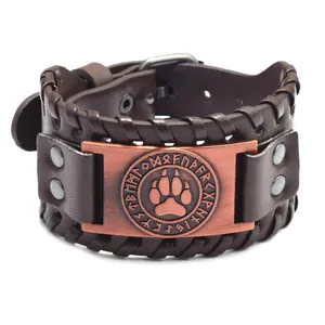 Dettaglio del bracciale vichingo in pelle con rune nordiche e placca in metallo a zampa.