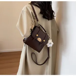 Sac à bandoulière en cuir marron vintage porté avec un trench beige pour la mode d'automne.