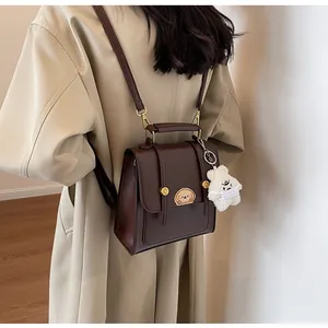 Vue de dos d'un sac à dos vintage en cuir marron foncé sur un mannequin en manteau beige