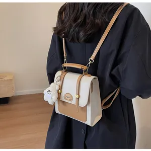 Vue arrière d'un élégant sac à dos vintage bicolore crème et beige avec un joli pendentif ours