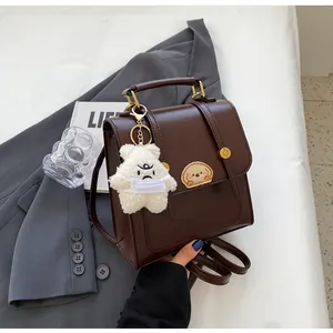 Détail d'un sac à dos vintage marron avec porte-clés ours mignon et écusson de pain