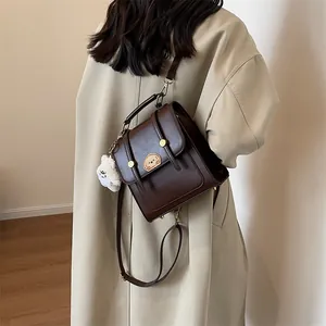 Sac bandoulière vintage en similicuir marron foncé avec écusson animal et breloque.