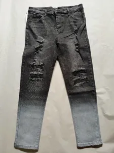 Detailed view of men's distressed skinny jeans with a grey gradient effect.