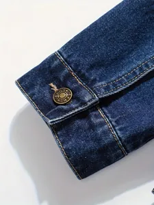 Close-up of blue denim jacket cuff with vintage bronze button and contrast stitching.