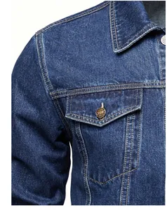 Close-up detail of blue denim jacket showing collar, shoulder and buttoned chest pocket.