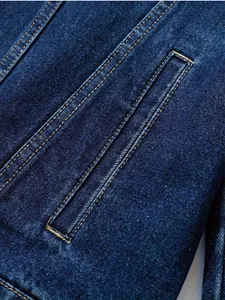 Macro view showing the high-quality tobacco stitching on a dark blue denim jacket pocket