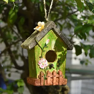 Dettaglio casetta per uccelli in resina con fiori e tetto rustico in iuta in giardino.