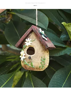 Dettaglio di casetta per uccelli in resina decorativa con trama di sacco e fiori bianchi