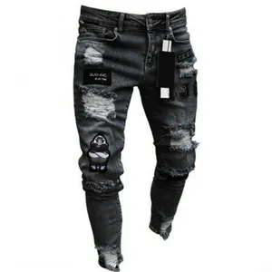 Close-up of distressed details and cartoon patches on dark grey men's jeans.