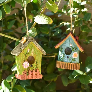 Primo piano di casette per uccelli decorative in resina appese in un rigoglioso albero