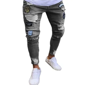 Detail view of men's grey ripped skinny jeans featuring military and peace patches