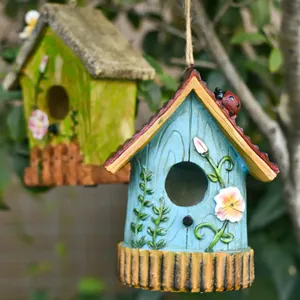Casette per uccelli decorative in resina con motivi floreali appese in un giardino verde