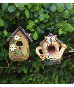 Dettaglio di casette per uccelli decorative in resina a forma di sacco e annaffiatoio.