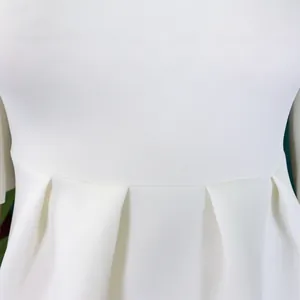 Detailopname van een witte effen jurk met geplooide taille en hoogwaardige stoftextuur