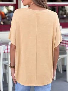 Back view of women's loose oversized camel yellow short sleeve t-shirt in casual outdoor cafe