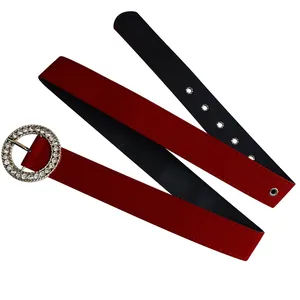 Detail view of a stylish red suede belt featuring a sparkling round rhinestone buckle.