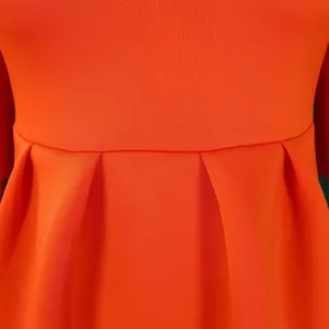 Gedetailleerde close-up van de geplooide taille op een levendige oranje cocktailjurk