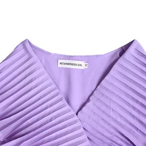Macro detail view of purple pleated dress neckline featuring the Metamorphosis Girl label