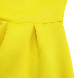 Detailopname van de taille van een gele jurk met elegante plooien en textuur