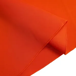 Gedetailleerde macroweergave van levendige oranje zomerjurkstof met fijne naden.