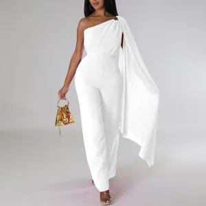 Detail showing the elegant white one-shoulder jumpsuit with a draped cape sleeve