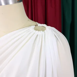 Detailed view of white one-shoulder fashion dress featuring a metal ring and soft draping