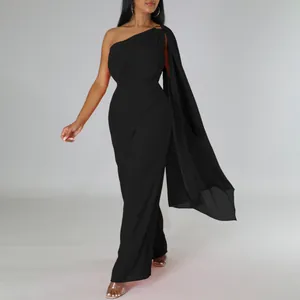 Full-length shot of an elegant black one-shoulder jumpsuit with a long flowing cape sleeve