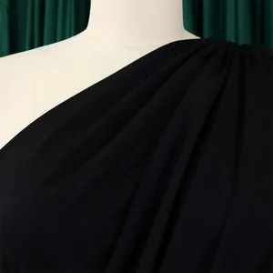 Detailed macro shot of black one-shoulder dress fabric texture and elegant pleats