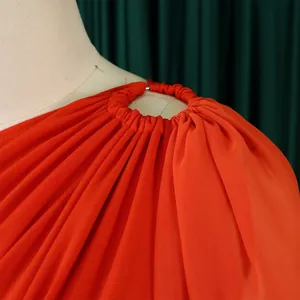 Close-up of elegant one-shoulder red jumpsuit with metal ring and pleated detail