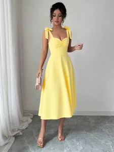 Volledig zicht op een elegante gele midi-jurk met stijlvolle geknoopte schouderbanden.