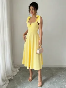 Elegante gele midi-jurk met strikjes op de schouders en hartvormige hals