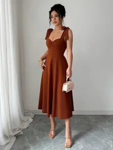 Stijlvolle terracotta midi-jurk met strikbandjes en een elegante uitlopende rok