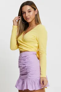 Elegante minifalda morada con volantes y diseño de cintura alta lucida por una modelo.